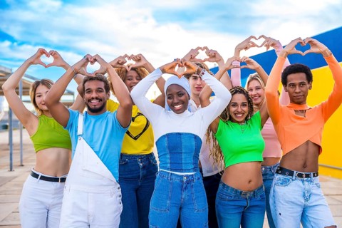 Multi-ethnic young people standing gesturing heart shape with hands outdoors in a urban space
