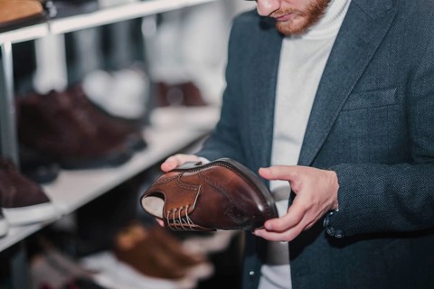 Man in business clothes chooses brown dress shoes in a store