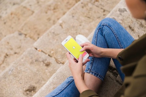 Woman sitting staircase using snapchat app smartphone