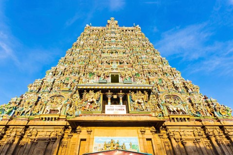 Centered west tower gateway of Meenakshi Amman Temple covered in colorful statues of gods on a blue