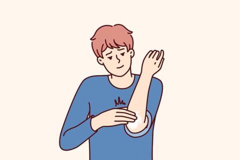 Man smears elbow with healing ointment after bruise or skin problems and acne. Young guy uses