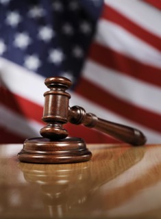 Wooden gavel on glossy table, The flag of USA in the background