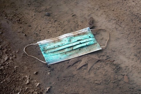 discarded used disposable face mask lying on ground in puddle - thrown away corona covid-19 masks