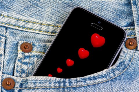 Smartphone with red hearts on the screen in a jeans pocket