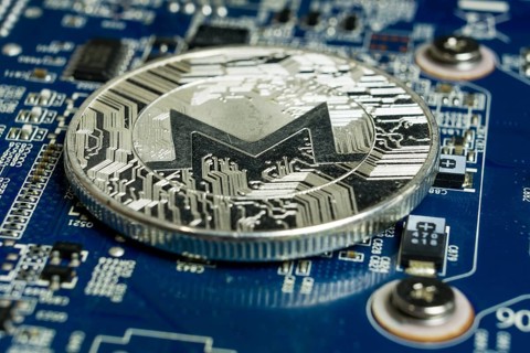 Photo of A single Monero coin on the blue computer motherboard