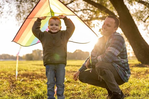 Father son playing together with colourful kite