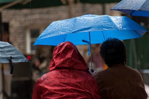 2 people sitting next to each other under umbrellas
