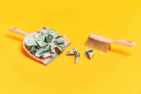 Creative layout with dustpan, hand brooms and crumpled money dollar bills on yellow background.