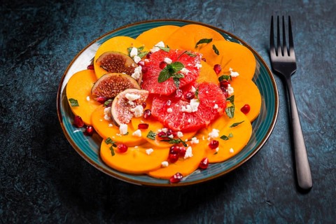 Healthy winter salad - Persimmon carpaccio salad with pomegranate, feta cheese, pink grapefruit and