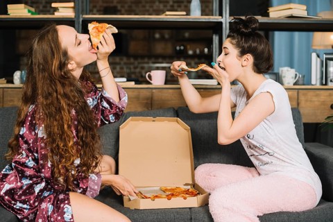 Two hungry young women eating pizza