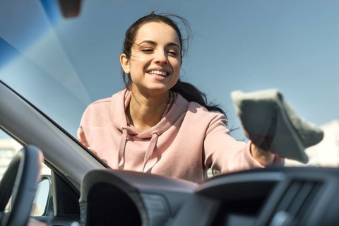 Woman cleaning front windscreen her car