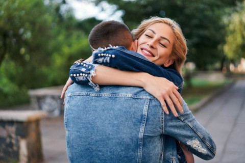 Happy meeting of two lovers hugging in the street. Young woman greeting her boyfriend embracing