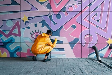 Street artist painting colorful graffiti on wall. Modern urban art concept