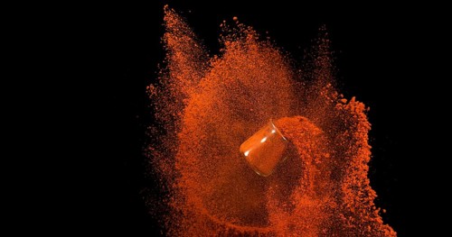 Paprika (capsicum) annuum, Powder in a Small Jar falling against Black Background