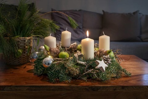 First Advent, wreath with one burning white candle and Christmas decoration on a wooden table in
