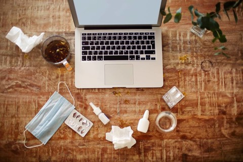From above various drugs and medical mask placed on table near plant twigs in vase and laptop with