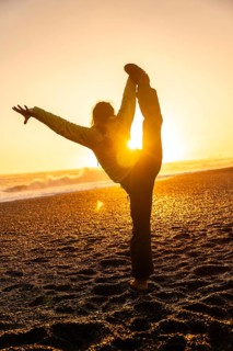 A woman is doing a yoga pose on a beach at sunset. Concept of relaxation and tranquility, as the