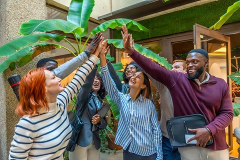 Diverse happy coworkers with hand put together for the unit of teamwork in a nice patio of a
