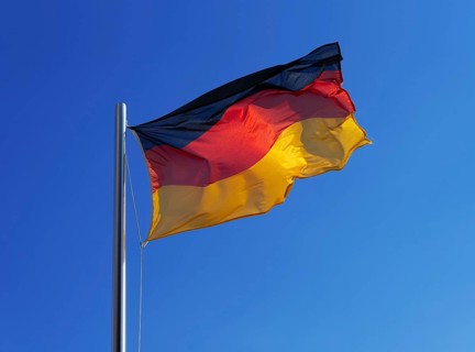 German flag, national flag in strong wind against blue sky