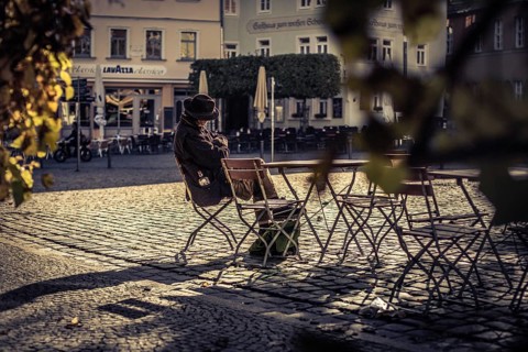 A person sits alone at a café table, reading relaxed in the autumnal atmosphere, On the streets in
