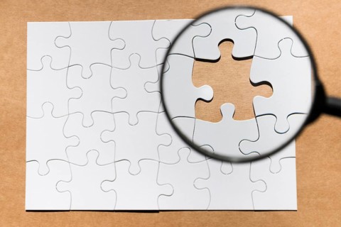 Magnifying glass missing puzzle brown paper textured backdrop