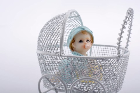 Little baby doll in baby carriage on a white background