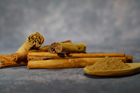 Cinnamon stick and ground cinnamon in a wooden spoon