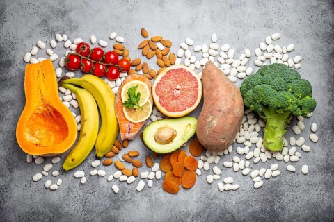 Vegetables, fruit and foods containing potassium over gray stone background, top view. Natural