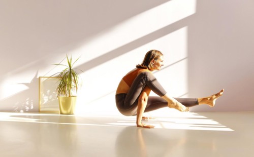 Full length of middle-aged sportive active woman in sportswear standing in yoga asana, doing