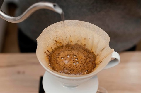 High angle male barista pouring hot water coffee filter