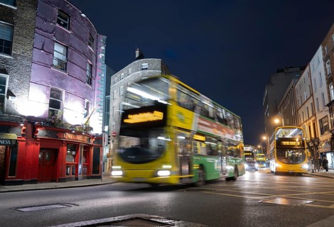 A Dublin bus speeds past Doyle's pub and on towards Trinity College at night time. Dublin, Ireland,