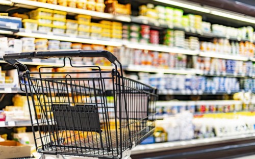 A shopping cart by a store shelf in a supermarket