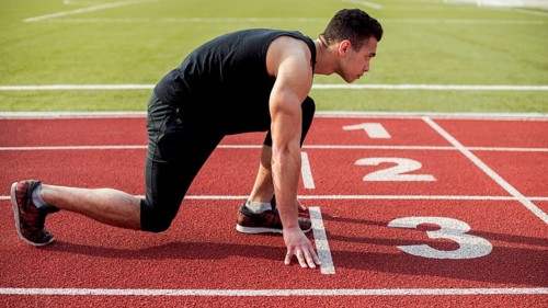 Side view male runner sprinter getting ready start race. High resolution photo