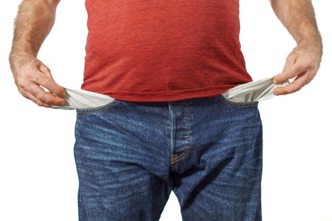 Man in blue jeans and red t-shirt showing his empty pockets white background and copy space