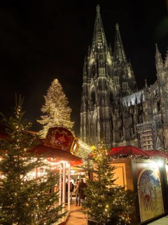Christmas market at night in front of an impressive, illuminated cathedral with decorated Christmas