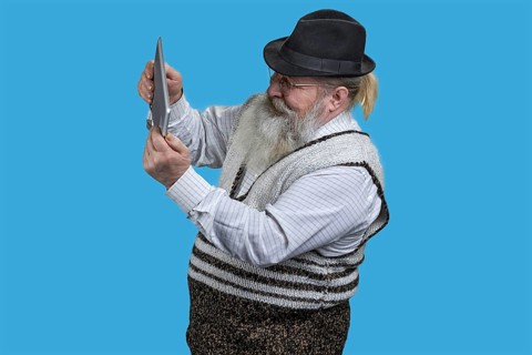 Portrait of excited senior man playing video game on tablet pc. Isolated on blue