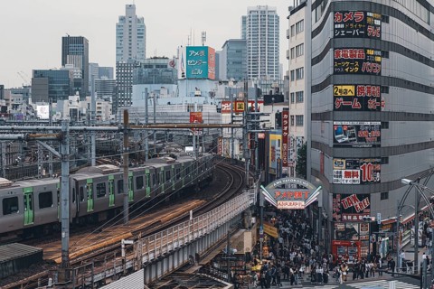 Moving train on the railway tracks next to the Ameyoko shopping street during the day in the Ueno