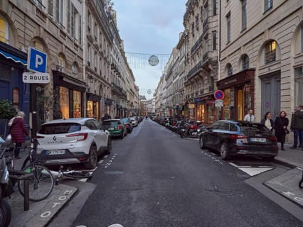 A busy city street at dusk with parked cars and pedestrians, Rue de L'Odeon .Paris