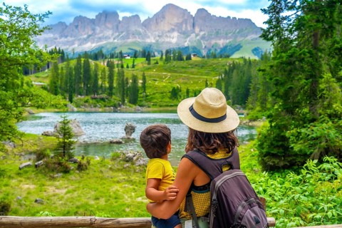 Mother carrying her son while enjoying breathtaking views of emerald waters at lake carezza,