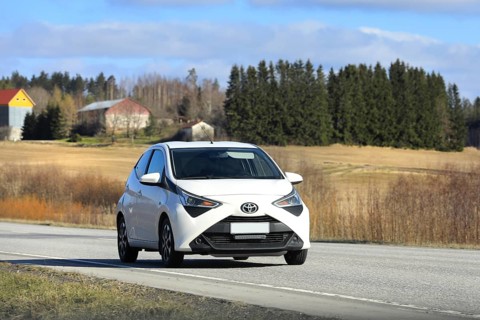 White Toyota Aygo city car, Second generation facelift model, at speed on highway. Salo, Finland.