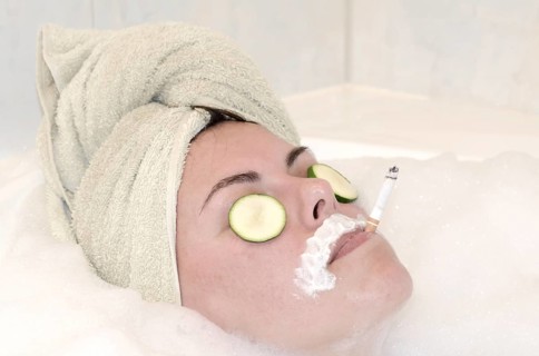 Headshot on a Woman Relaxing in the Bathtub with a Towel on Her Head and Smoking a Cigarette in a