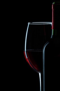Bottle and wine glass with red wine close-up on white background
