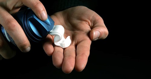 Hand of Woman and shaving foam against Black Background