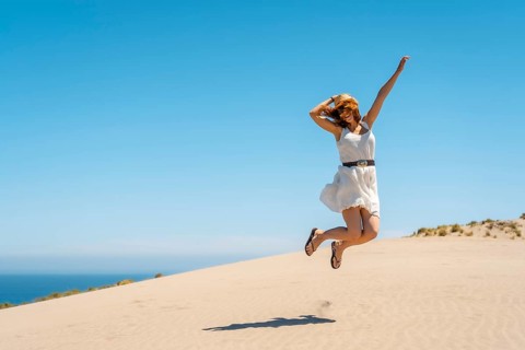 Happy woman jumping in a view point with sea views in Cabo de Gata, Spain, Europe