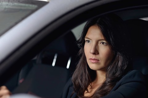 View through the windscreen with reflections of lights of a serious young woman driving her car at