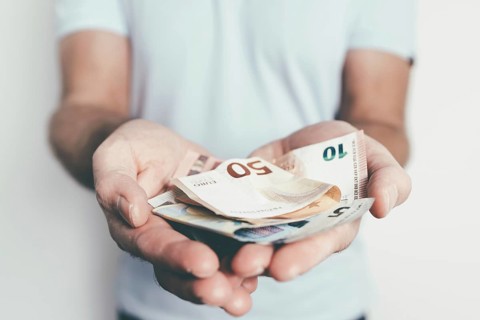 close-up of hands of caucasian man offering or handing over money to someone else