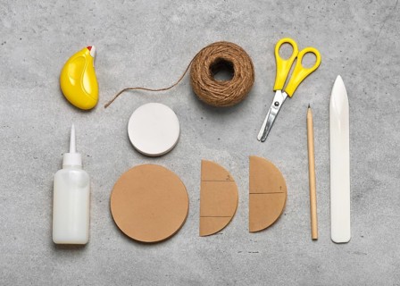 Workplace with craft equipment: brown and white coffee filters, glue, scissors, pencil, jute twine,