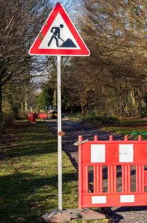 Red and white roadblock and roadworks sign closing a park path for construction