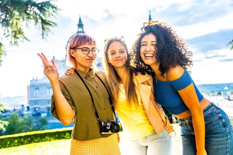 Happy female travelers gesturing success while standing in a city viewpoint in a park during sunet