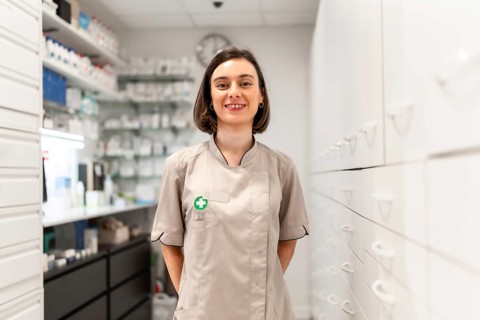 Portrait of a young woman pharmacist standing in the storage room smiling at camera
